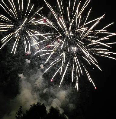 Feu d'artifice éclatant dans le ciel sombre avec traînées blanches et rouges